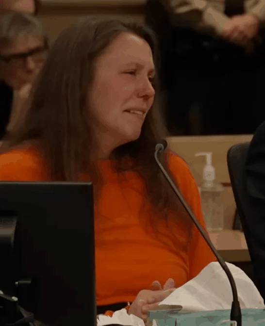 Bergman covers her face with hands in handcuffs