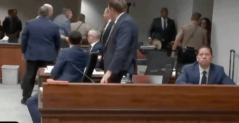 Adrian Gonzales sits stoically at the defense table as chaos erupts behind him in the courtroom