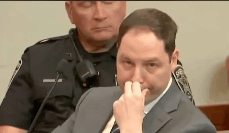 Brendan Banfield watching testimony with hand raised to face