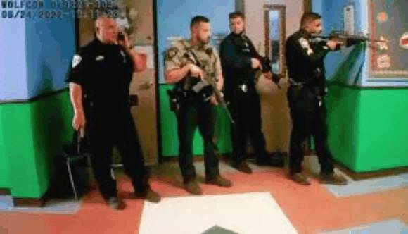 Multiple officers standing in school hallway with weapons