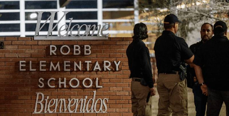 Robb Elementary School sign with investigators outside at night